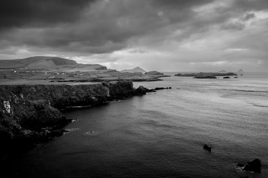 Dramatic black and white photograph of sea cliffs under a cloudy sky in Ireland.