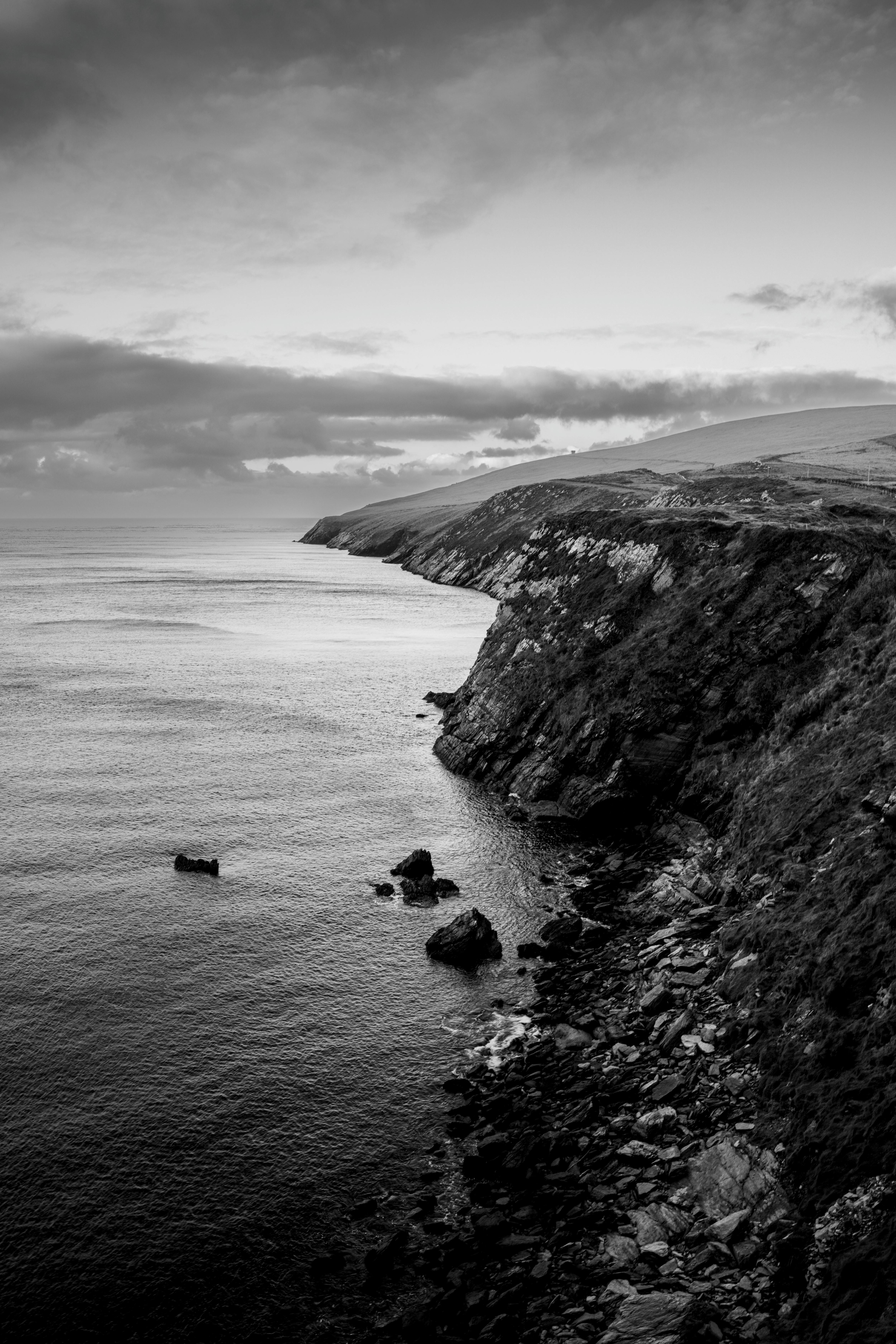 Stunning black and white photo of majestic sea cliffs in Ireland under a cloudy sky.