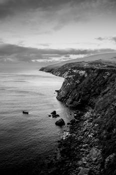 Stunning black and white photo of majestic sea cliffs in Ireland under a cloudy sky.