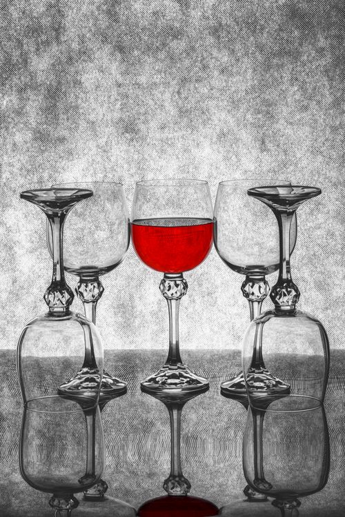 Free Red wine glass stands out prominently among clear goblets, creating an artistic contrast. Stock Photo