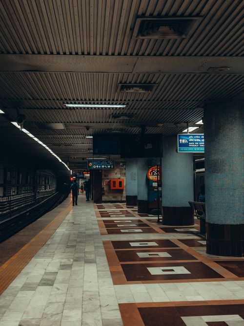 Free Empty subway station with tiled flooring and overhead lighting, ready for urban exploration. Stock Photo