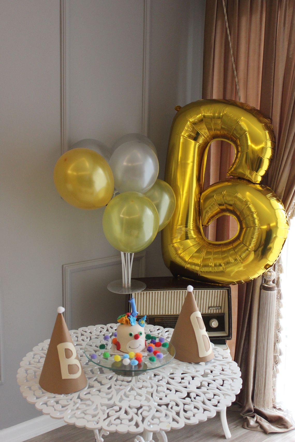 Colorful birthday celebration setup with balloons, cake, party hats, and festive decorations