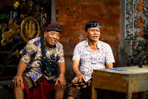 Free Two Balinese men in traditional attire sitting outside a decorated temple in Bali, Indonesia. Stock Photo