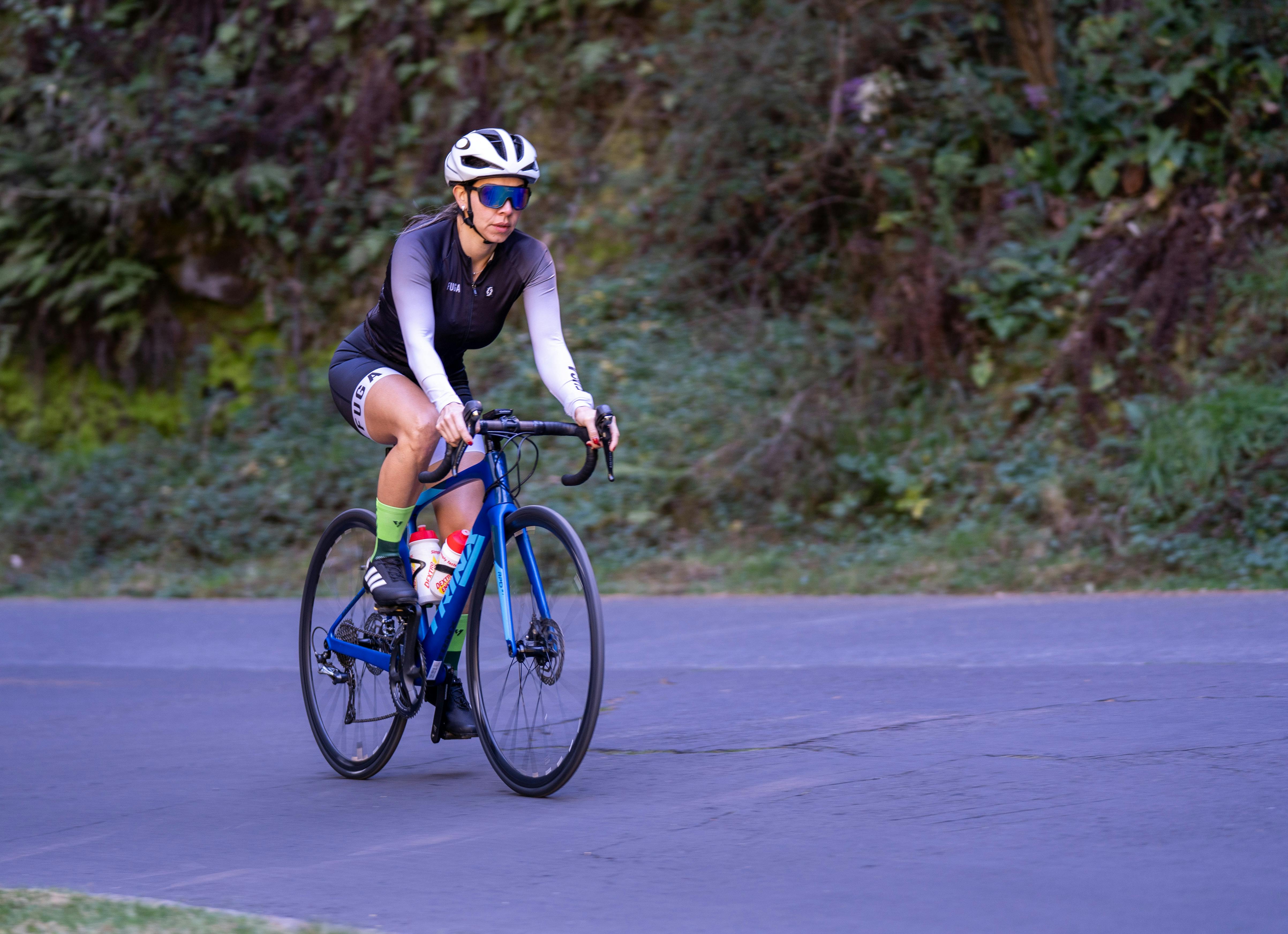 Female cyclist riding a road bike on a quiet trail during the day.