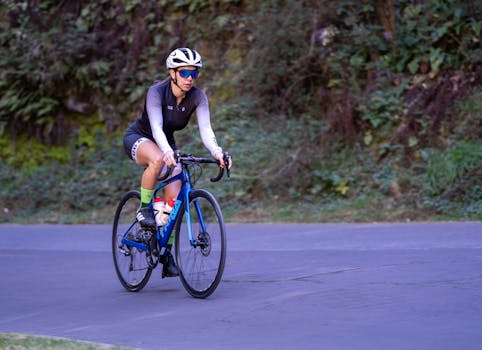 Female cyclist riding a road bike on a quiet trail during the day.