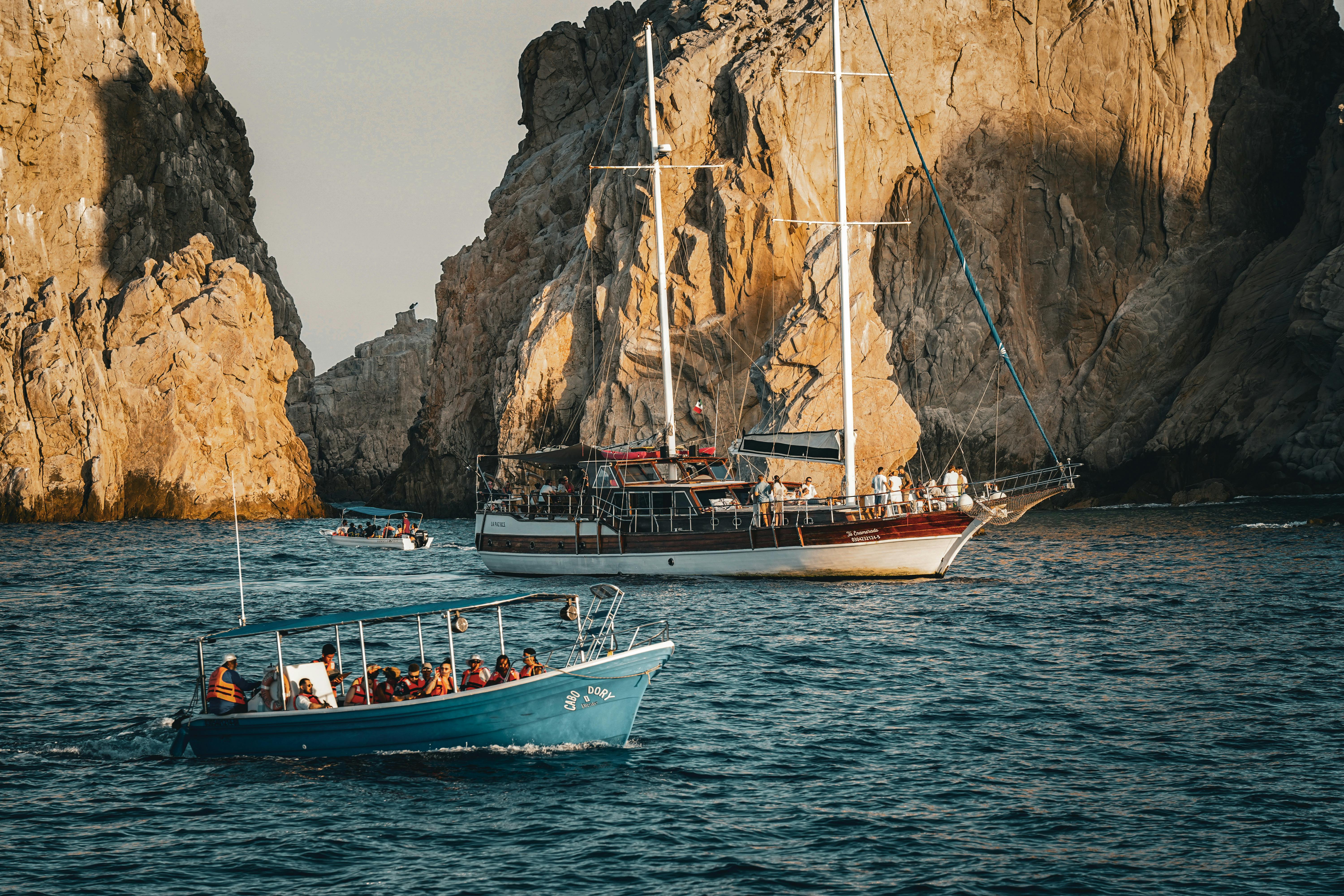 Boats navigate through stunning rocky coastal cliffs during daytime adventure tour.