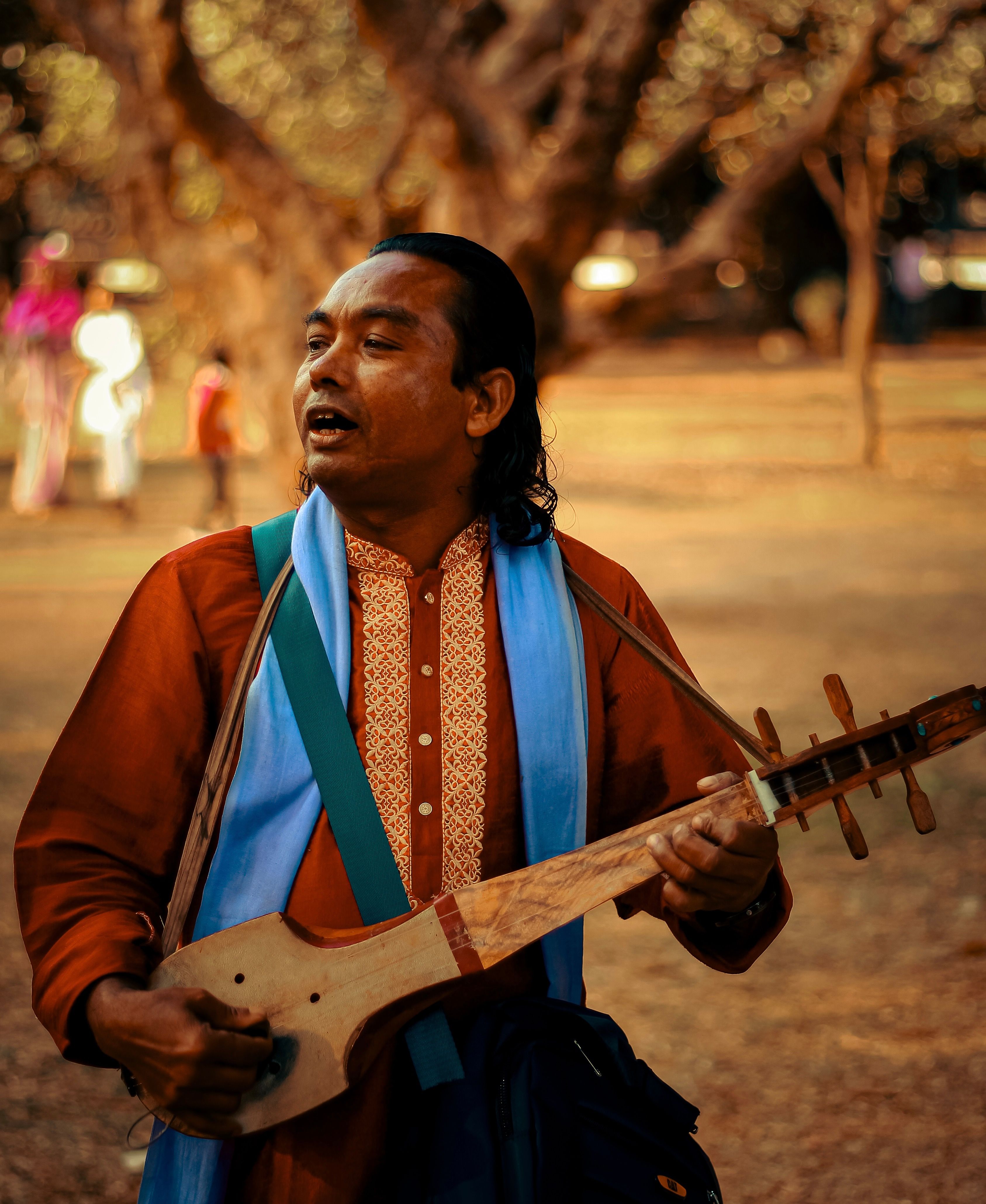 A musician performs outdoors with a traditional instrument in a Dhaka park, Bangladesh.