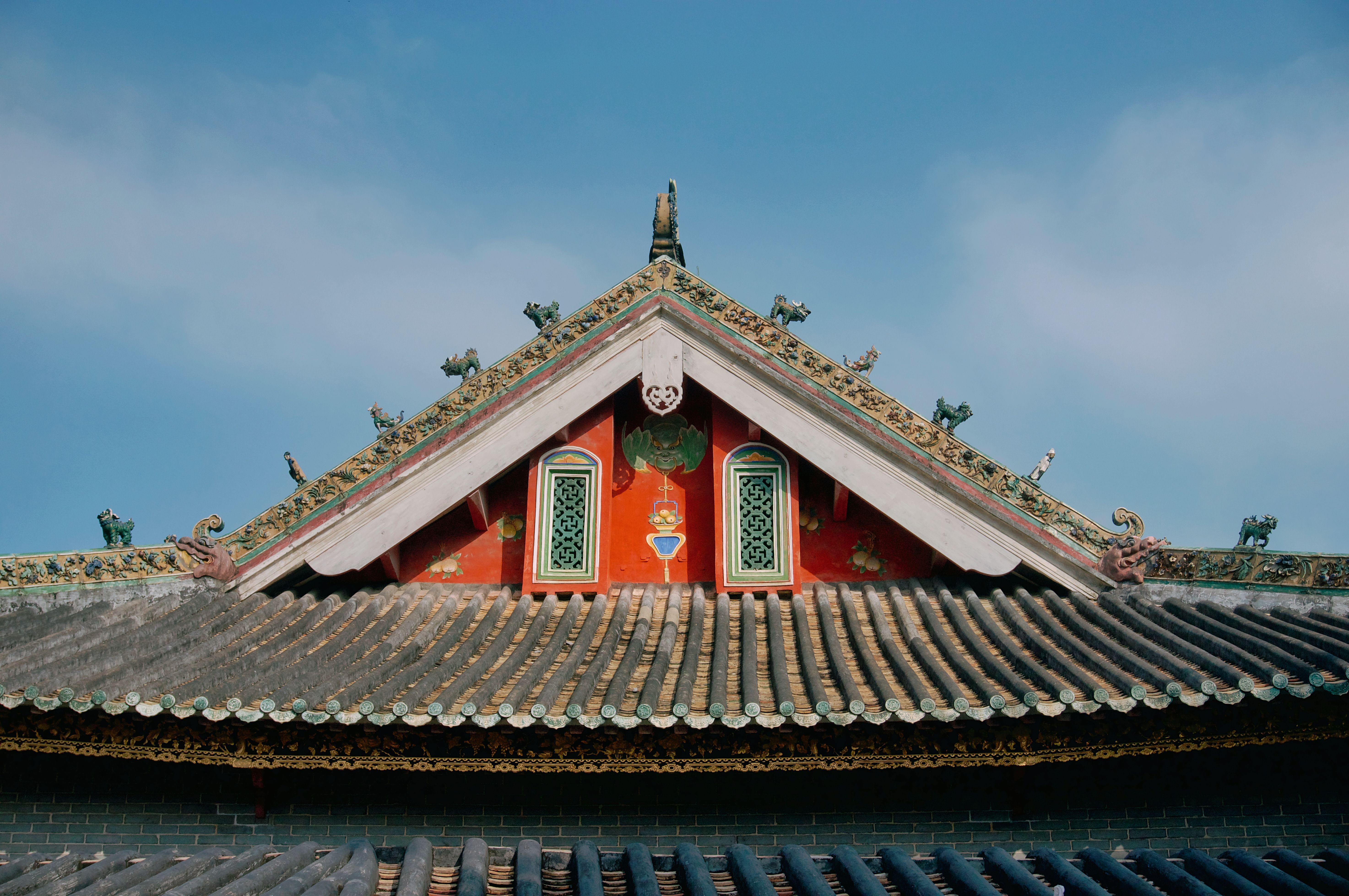 Beautiful traditional Chinese roof with intricate artwork against a clear sky.