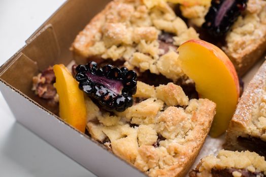 Close-up of fresh blackberry and peach crumble bars in a box, perfect dessert.