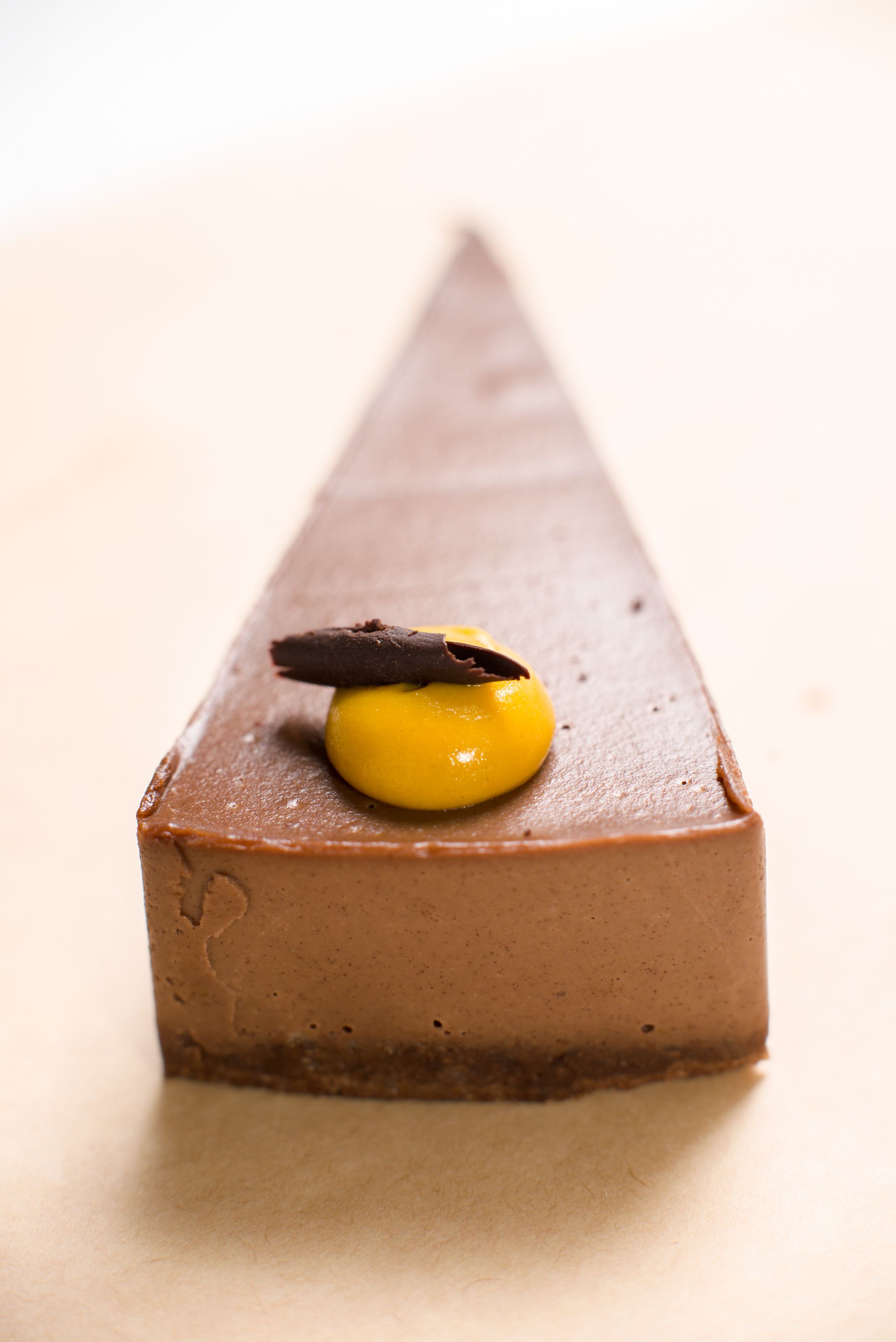 Close-up of a gourmet chocolate mousse cake slice with a yellow topping.