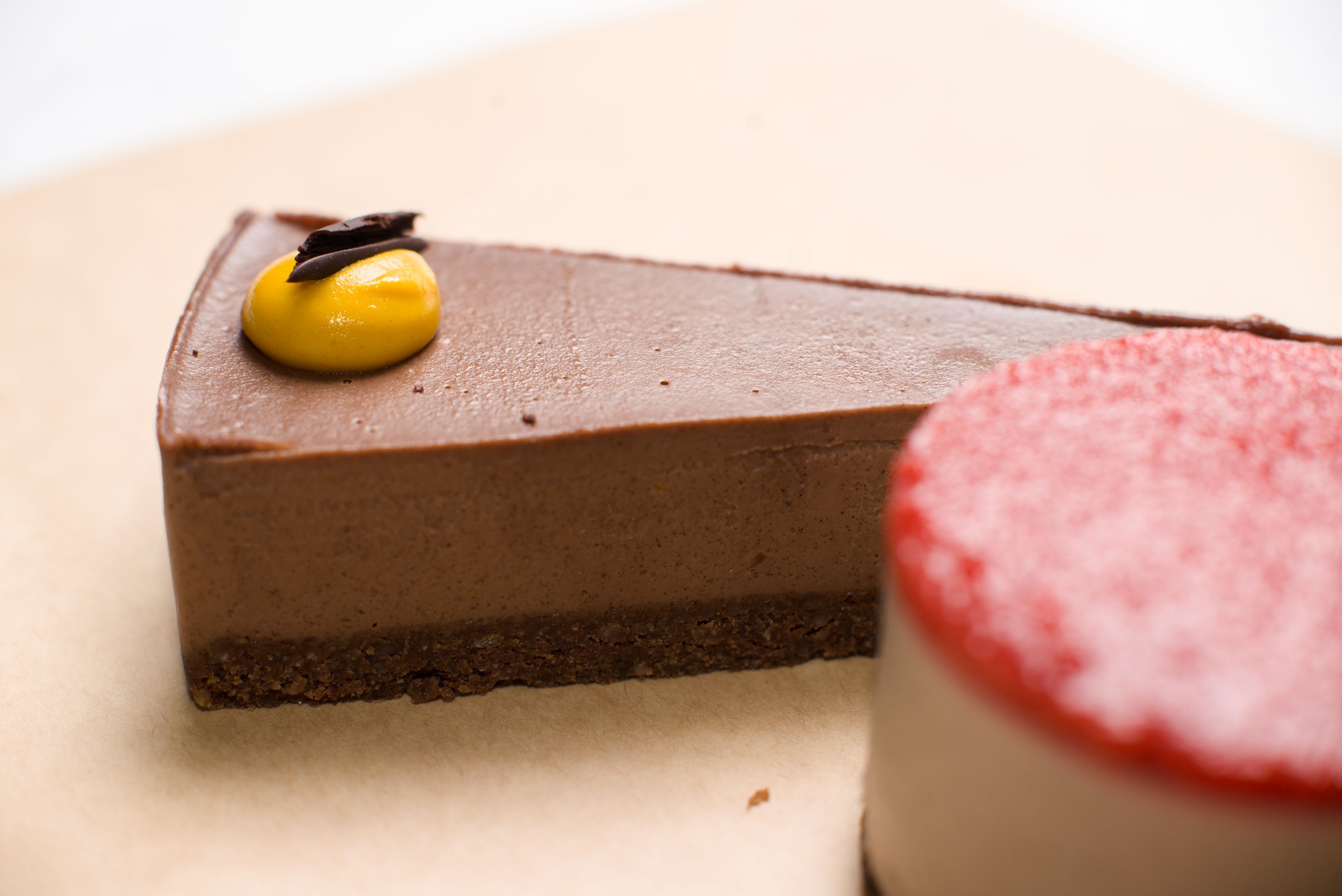 Slice of lactose free vegan chocolate cheesecake on a plate with chocolate drizzle