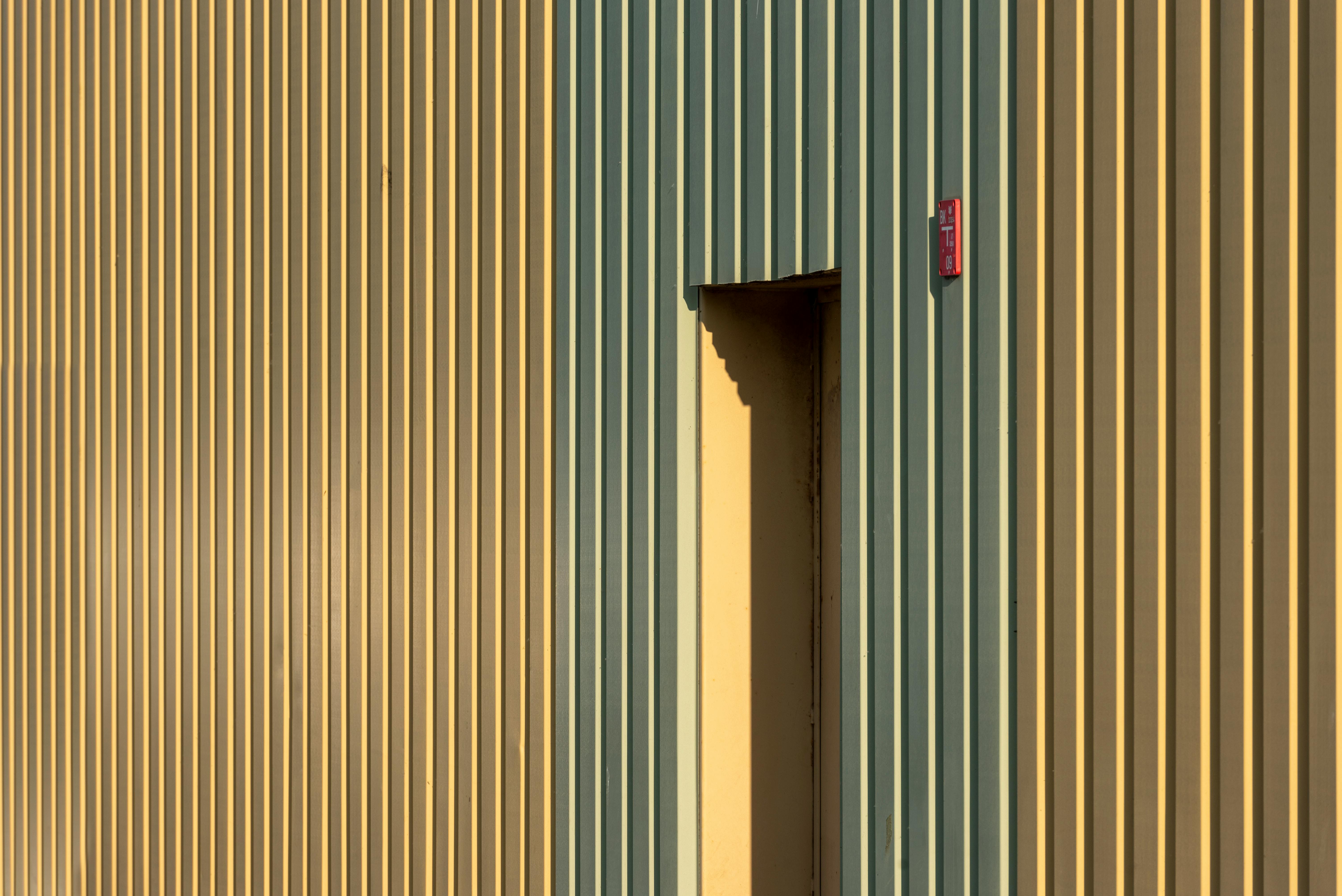 gratis Moderne industriële muur met verticale groene en gele strepen en een deur. Stockfoto