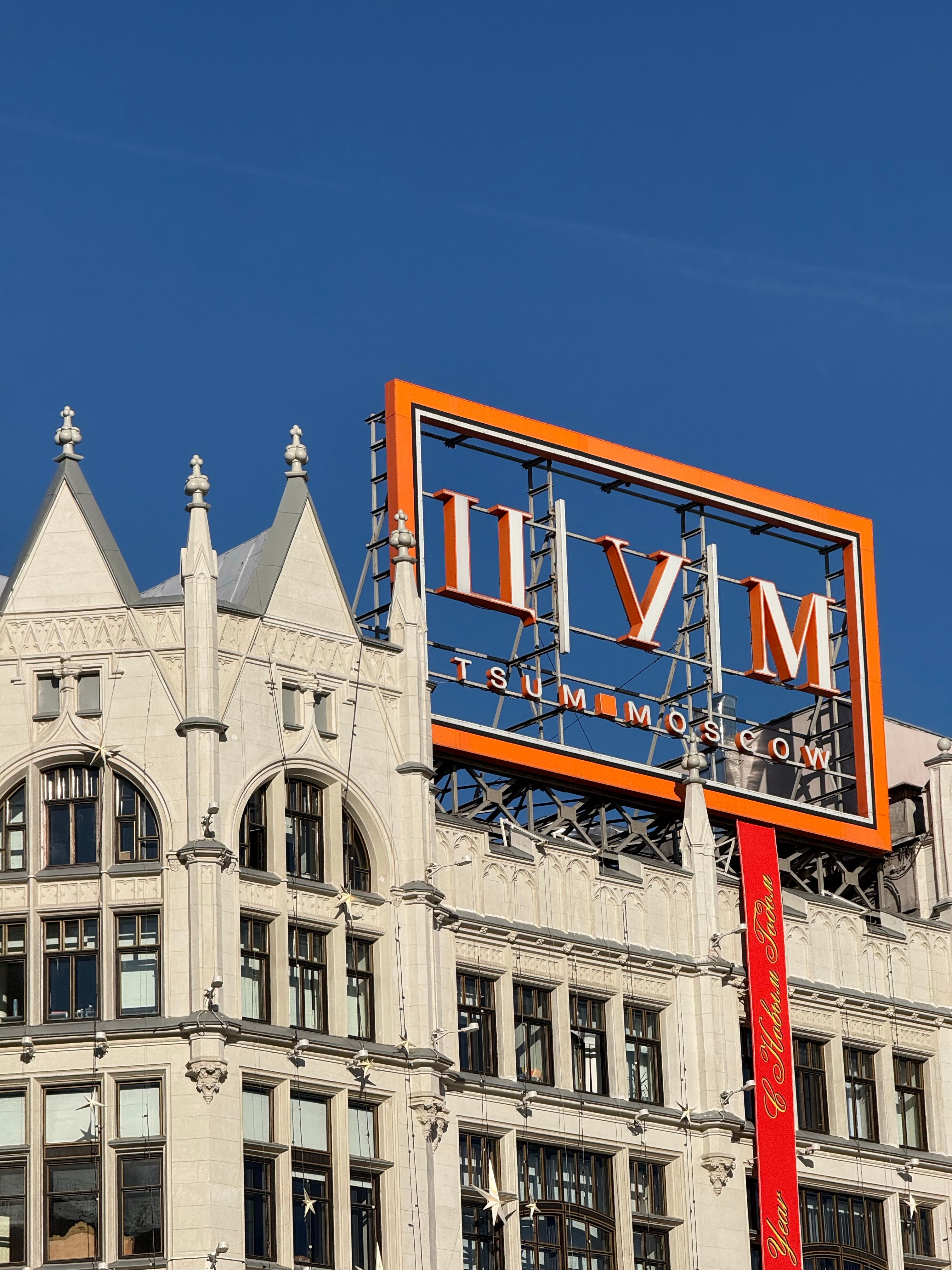 TsUM department store sign on a historic building in Moscow under clear blue skies.