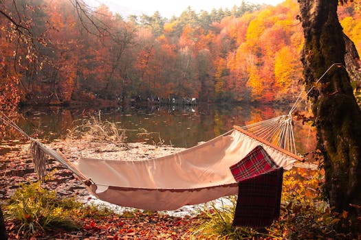 Tranquil autumn scene with hammock by a lake surrounded by vibrant fall foliage.