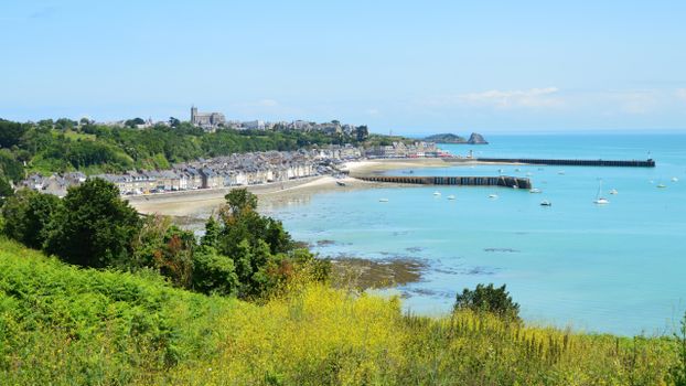 Picturesque view of Cancale Bay, France, with lush greenery, quaint houses, and a serene harbor.