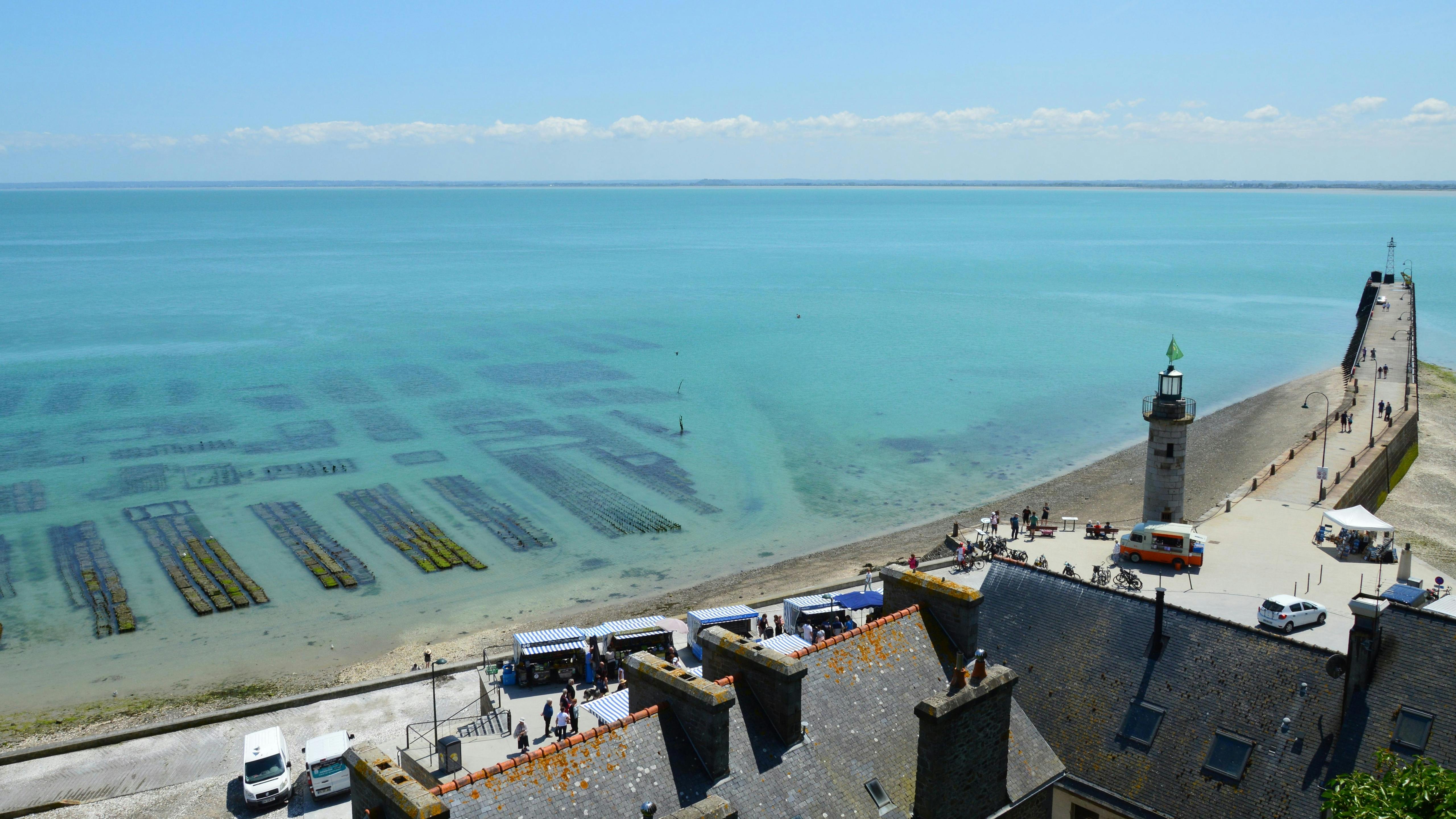Cancale oyster beds at sunrise with wooden huts on stilts, traditional flat-bottomed boats, and tidal flats under soft Breton morning light in Brittany, France