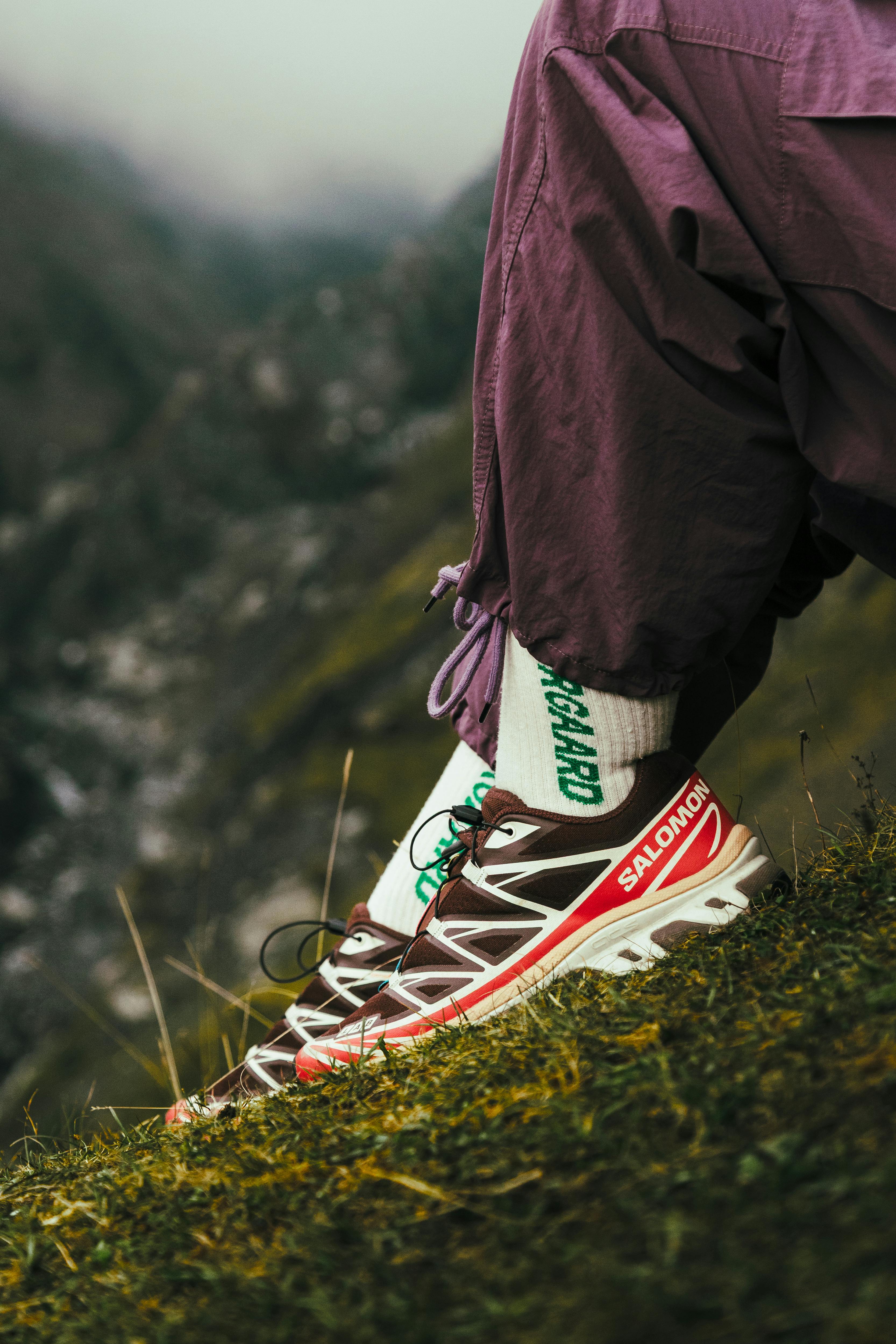 Close-up of hiker's foot in Salomon shoe on a scenic mountain trail, showcasing outdoor adventure.