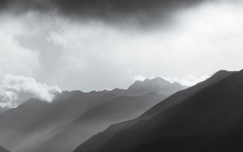 Free Monochrome view of misty mountain ranges under dramatic cloud-filled sky. Stock Photo