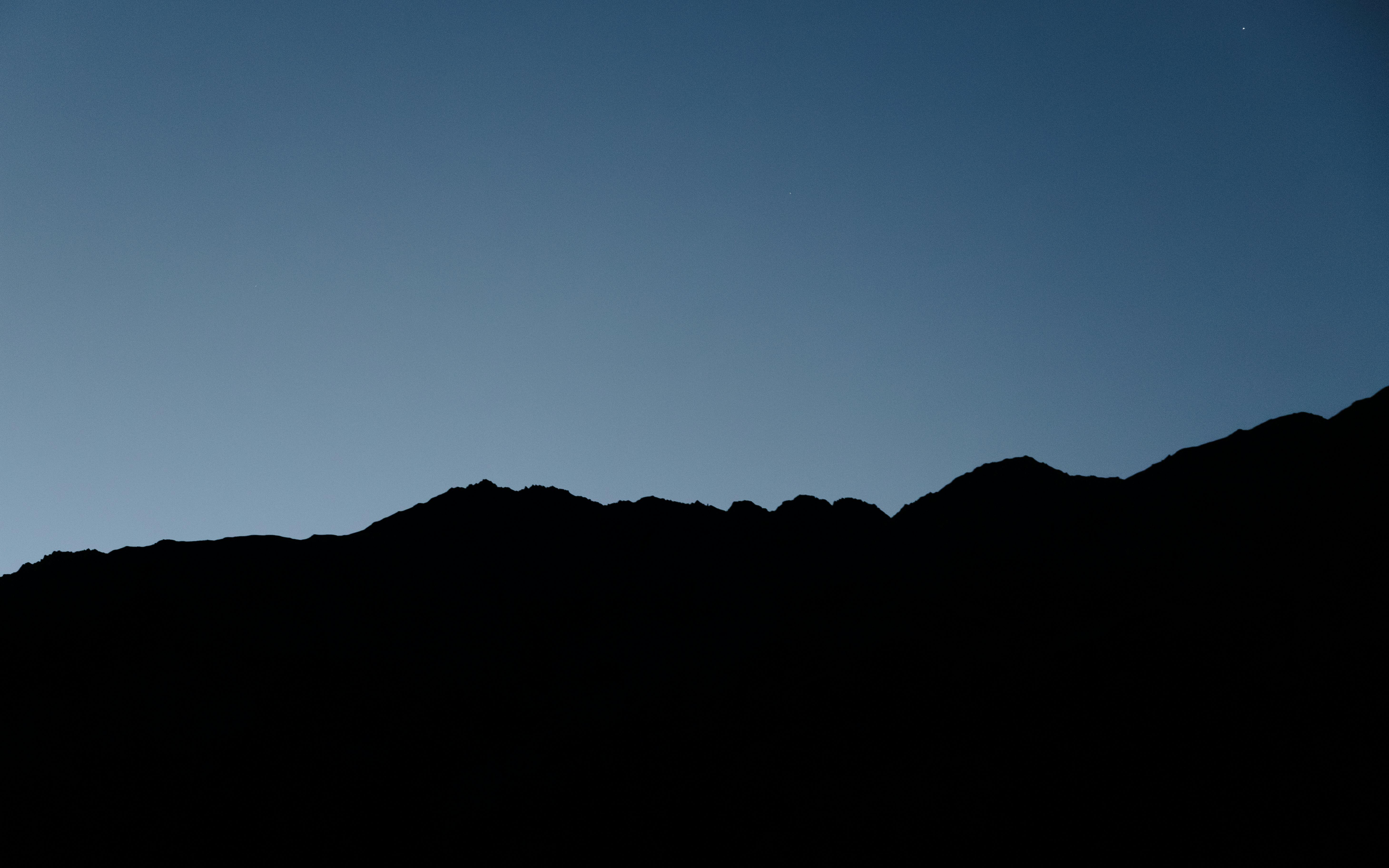 무료 황혼의 하늘 아래 산봉우리의 평화로운 실루엣이 고요하고 평화로운 분위기를 조성합니다. 스톡 사진