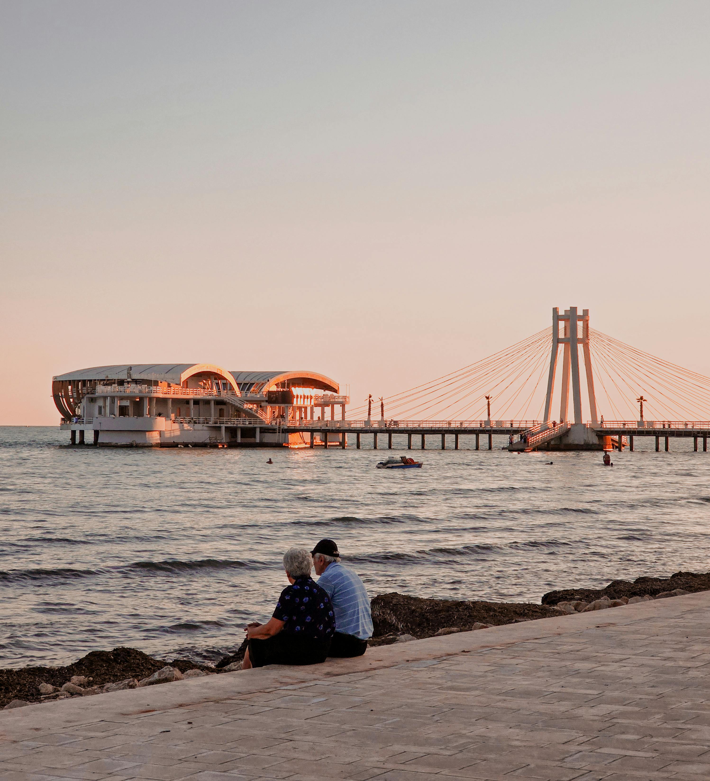 A peaceful sunset view at Durres Beach, Albania, with a couple sitting by the pier.