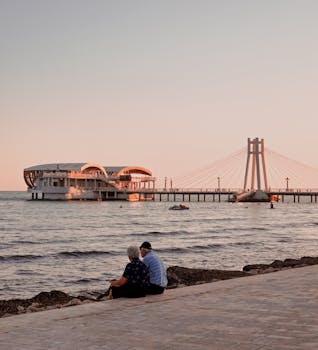 A peaceful sunset view at Durres Beach, Albania, with a couple sitting by the pier.