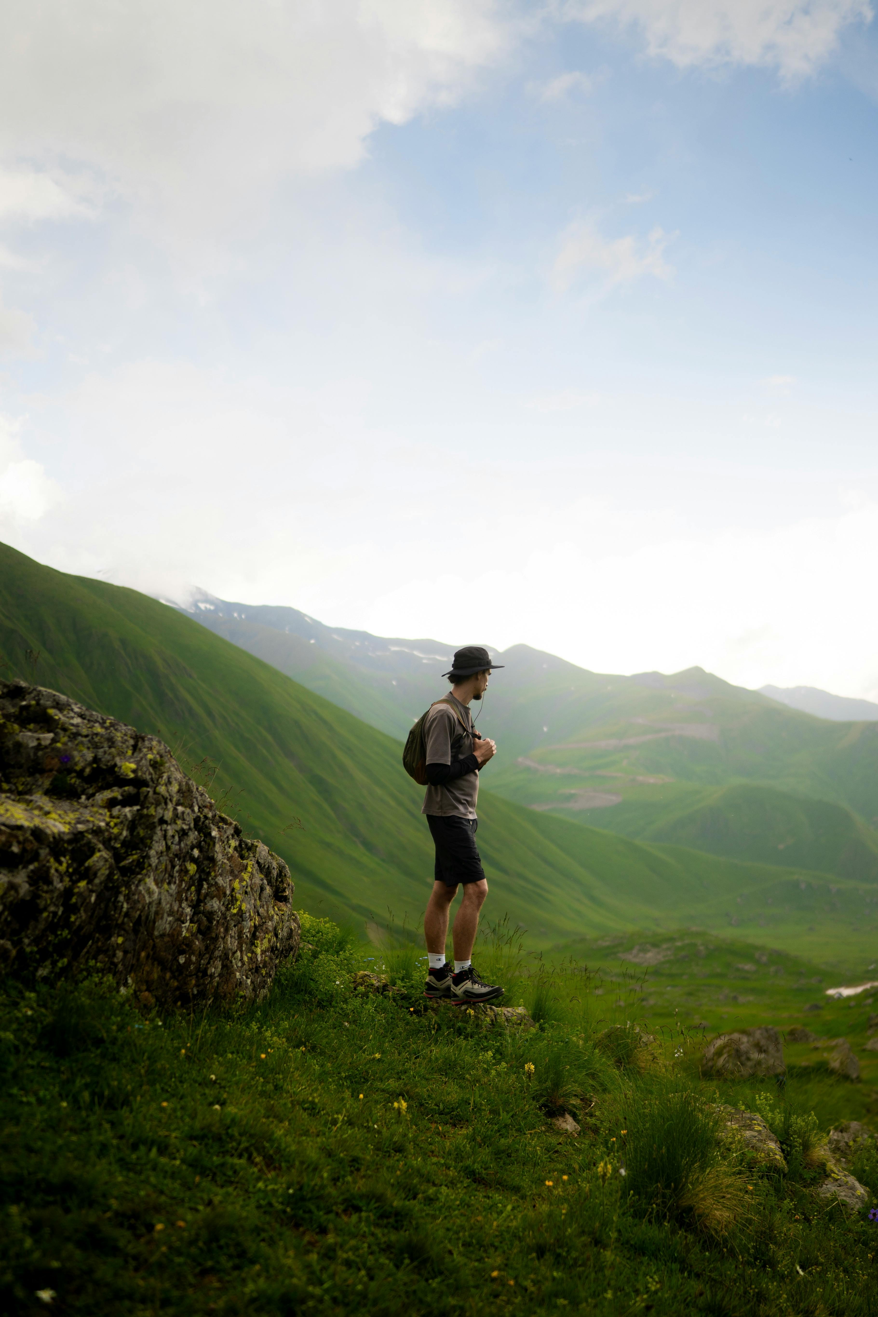 A lone hiker explores the stunning green hills of Georgia, embracing nature.