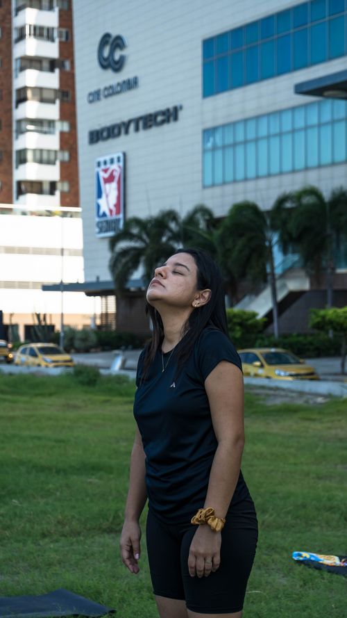 Free A woman in activewear relaxes outdoors near Bodytech gym, enjoying fresh air. Stock Photo