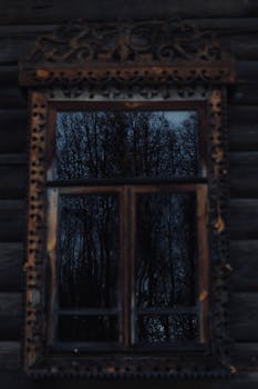 Beautiful reflection of trees in a detailed vintage wooden window at twilight.