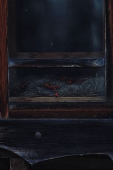 A rustic wooden window with hay and red berries inside, creating a vintage feel.