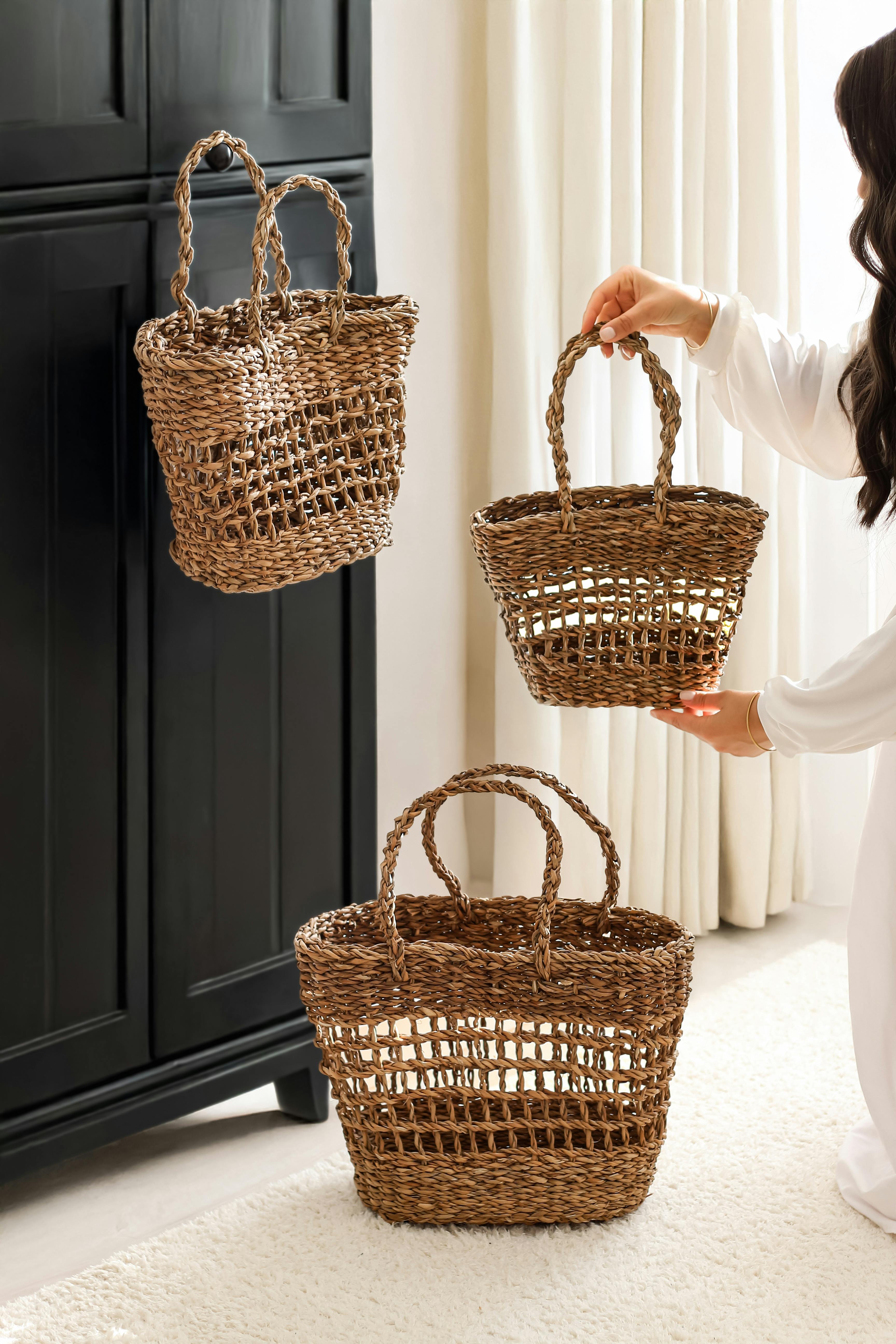 Stylish woven straw baskets being arranged by a woman in a bright, cozy room.