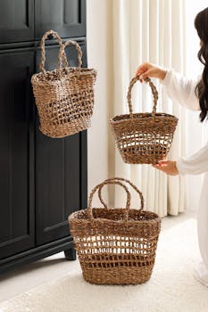 Stylish woven straw baskets being arranged by a woman in a bright, cozy room.