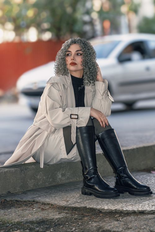 Free Fashion-forward woman with curly hair poses stylishly in an urban environment. Stock Photo