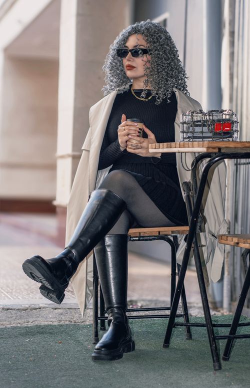 Free Fashionable woman in stylish outfit sitting at a cafe table outdoors. Perfect blend of chic and casual. Stock Photo
