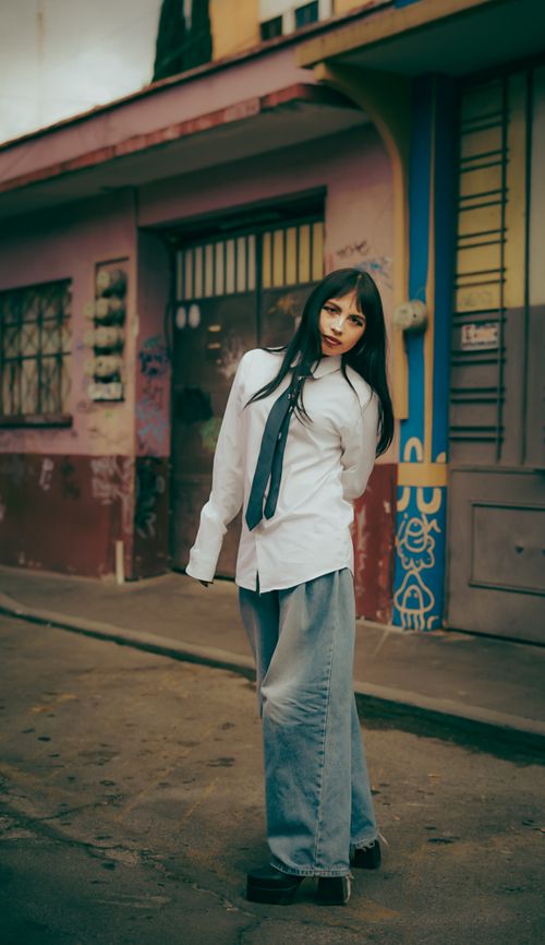 Free Stylish young woman poses confidently on a colorful urban street with artistic backdrops. Stock Photo