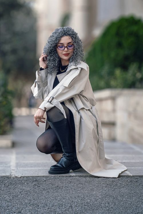Free Confident woman with curly hair poses outdoors in a stylish trench coat. Stock Photo