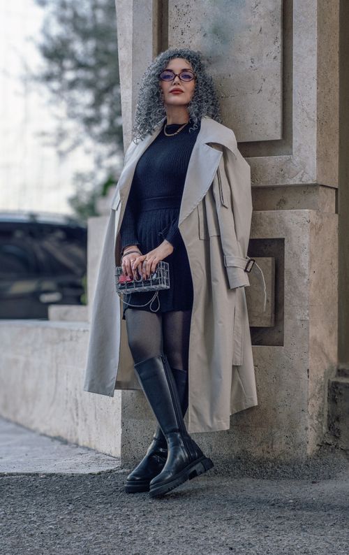 Free A fashionable woman in a trench coat poses confidently in an urban setting, showcasing modern style. Stock Photo