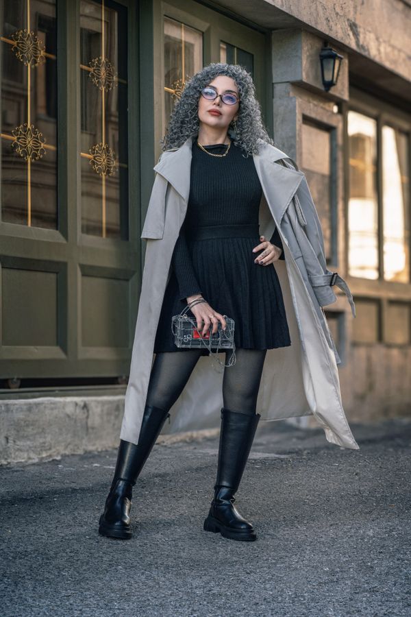 Woman in trench coat with knit dress and boots