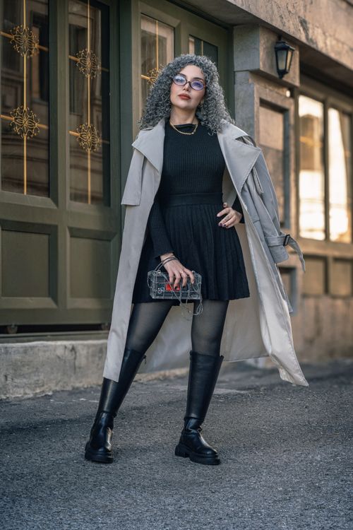 Free Fashionable woman in trench coat and boots posing outdoors. Modern city vibe. Stock Photo