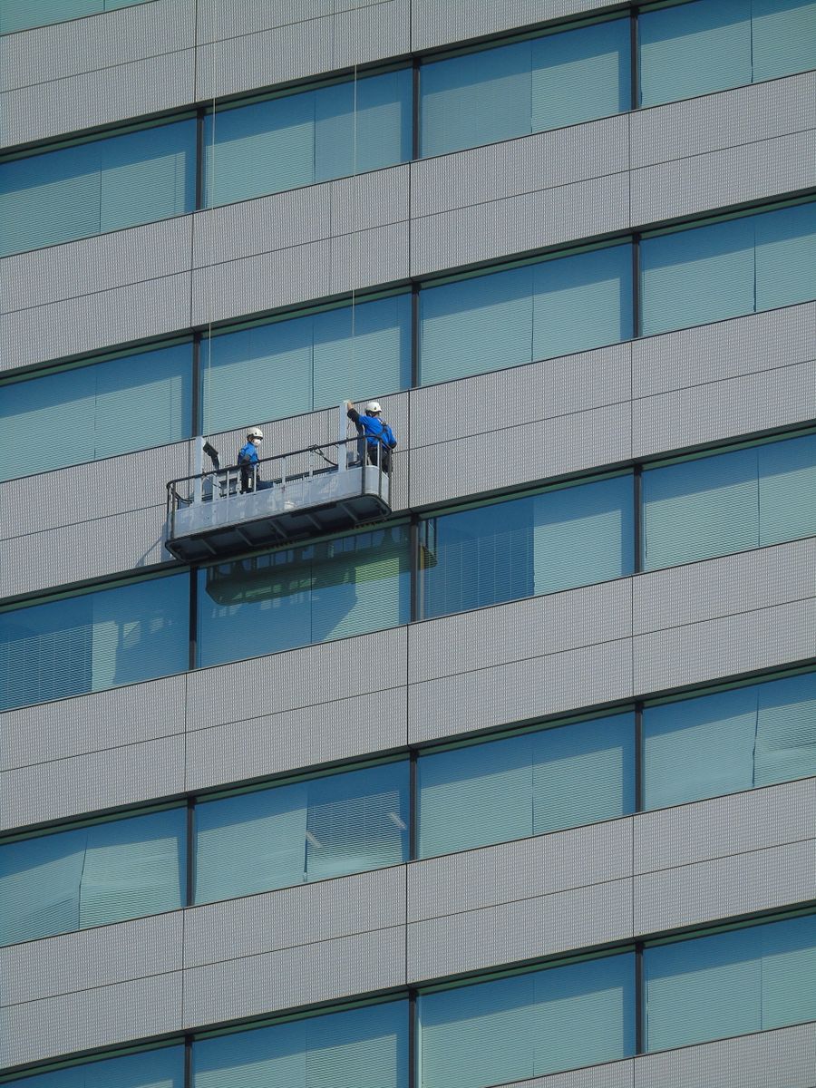 Workers on a suspended platform on a glass facade