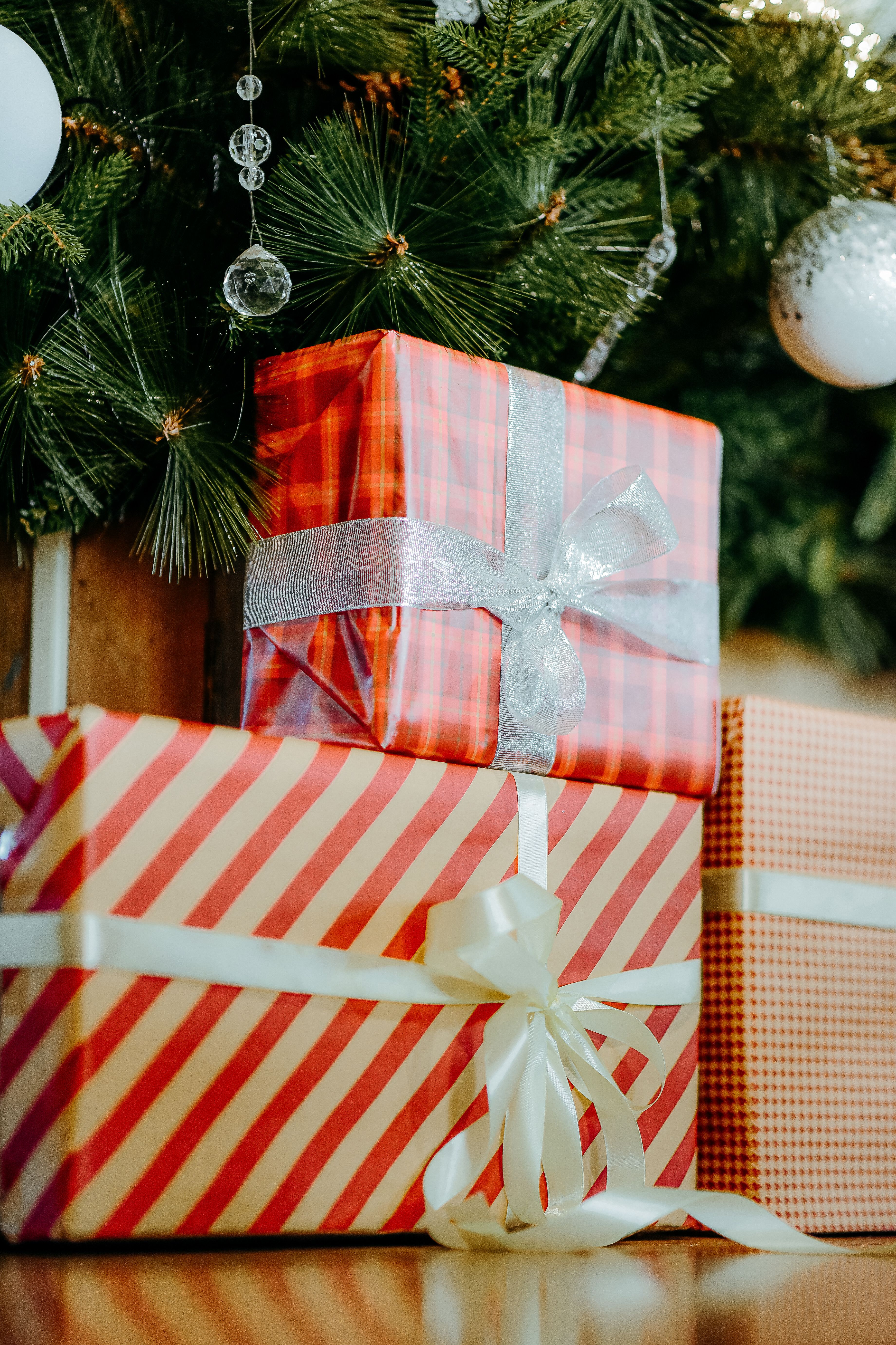 Close-up of wrapped presents beneath a decorated Christmas tree, evoking holiday cheer.