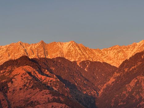 Captivating image of the Himalayas at sunset with snow-capped peaks glowing warmly.
