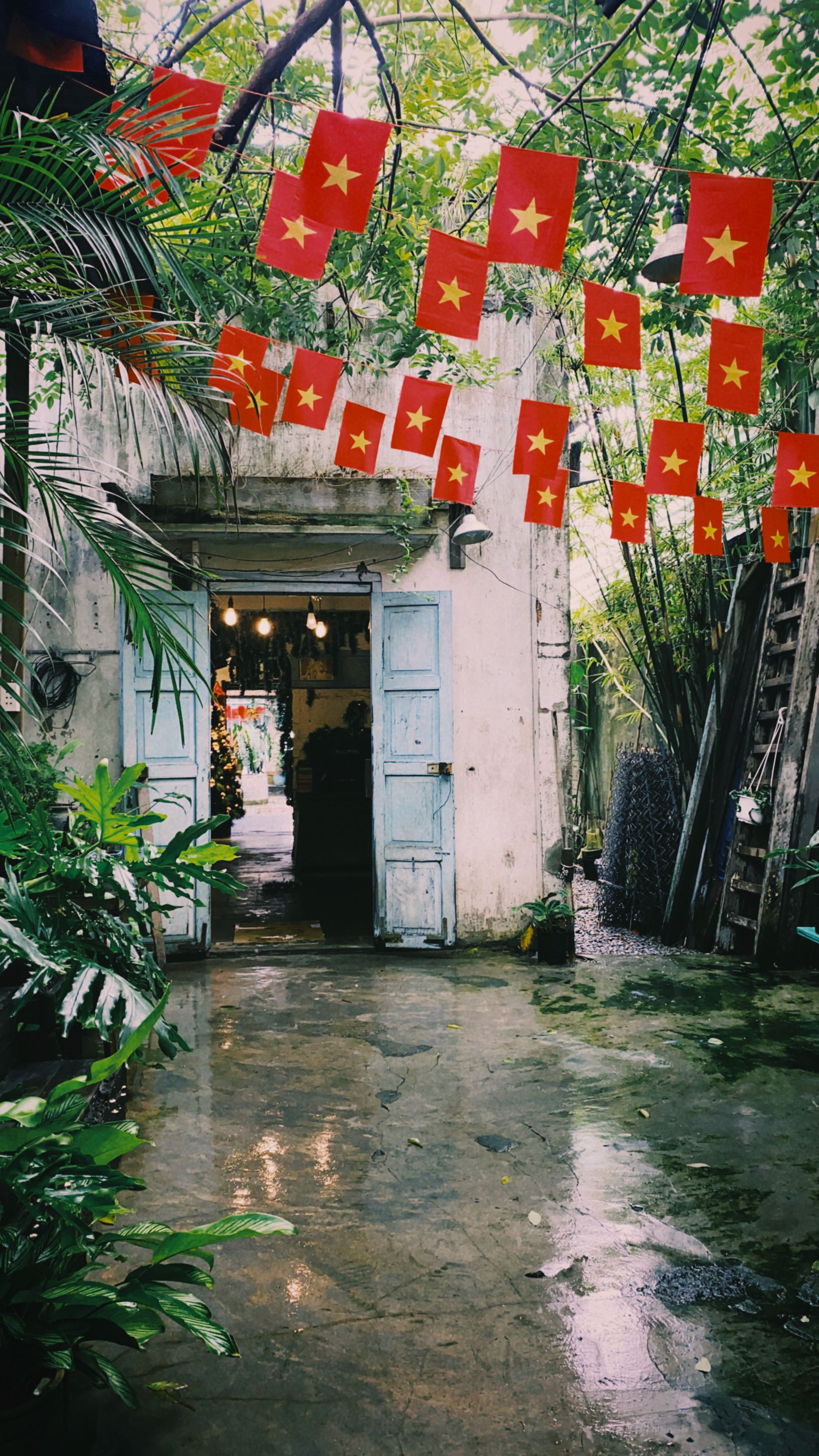 Vietnamese courtyard with red flags and lush greenery, vibrant cultural setting.