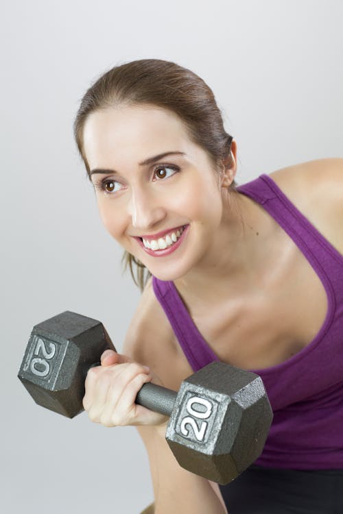 Mulher Vestindo Camiseta Roxa Segurando Halteres A 20 Kg