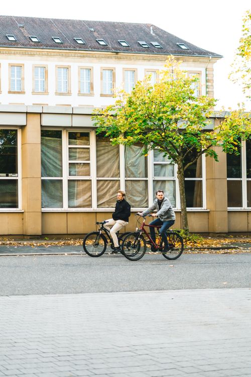 Free Two cyclists enjoy a sunny ride in Karlsruhe, showcasing the city's urban bike culture. Stock Photo
