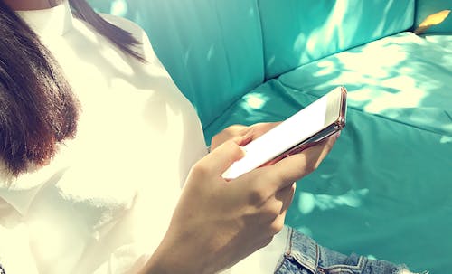 Free Woman Wearing White Top Holding Black Smartphone Stock Photo