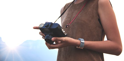 Woman Holding Camera Near Mountain