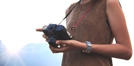 日出时分，一个女人手持老式相机在户外拍摄，特写镜头捕捉着大自然的美丽