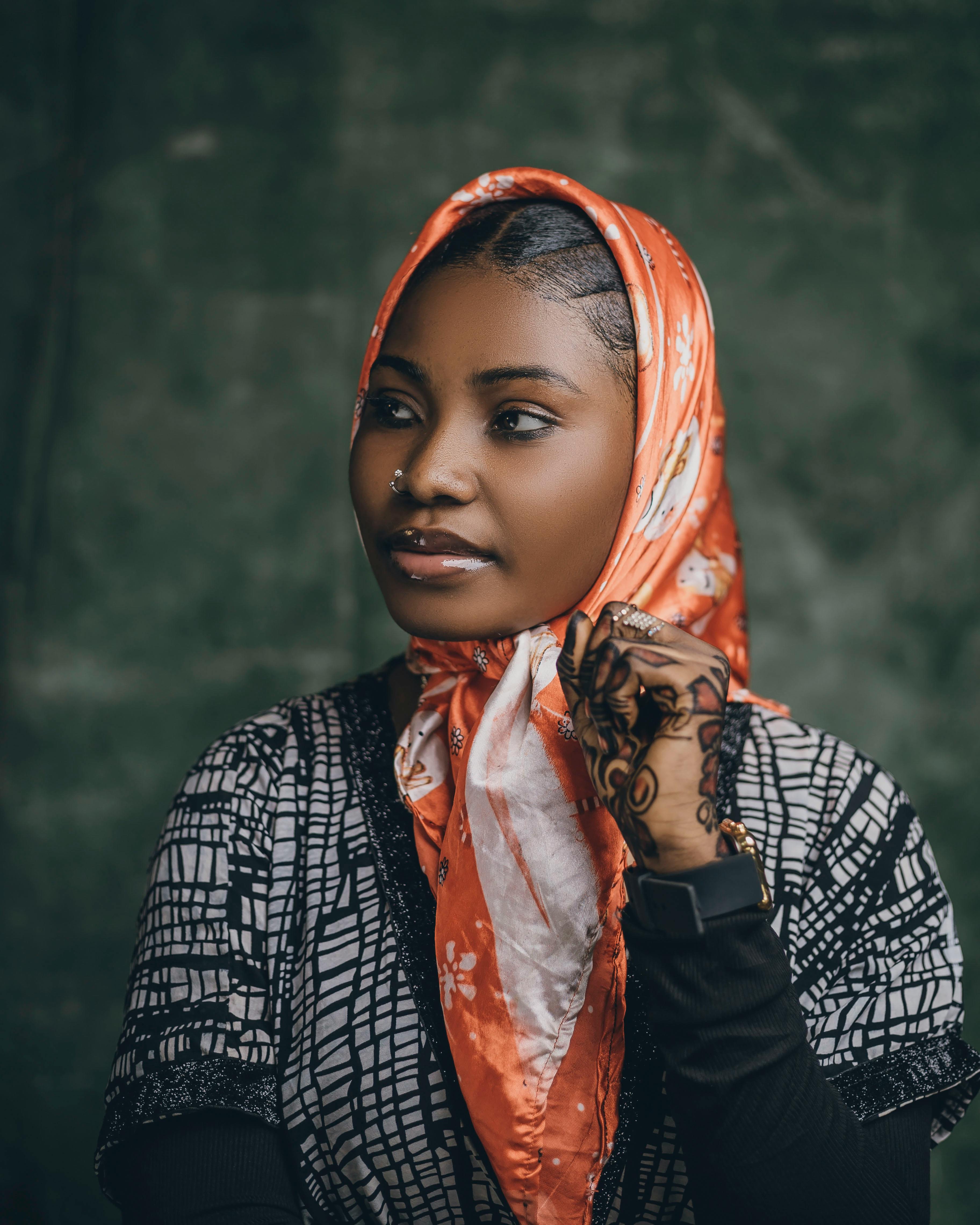 Gratis Portrett av en kvinne med henna, piercinger og et fargerikt hodeskjerf mot en mørk bakgrunn. Arkivbilde