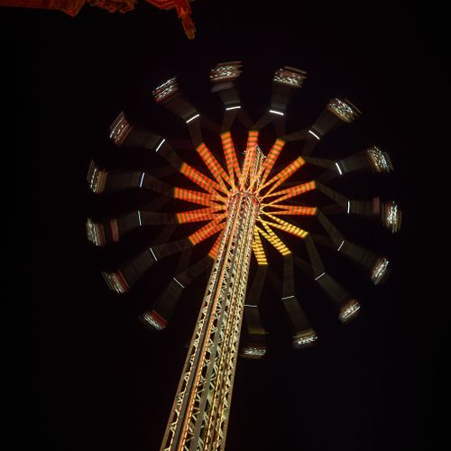Free Dynamic and vibrant image of a spinning carnival ride at night against a clear sky, featuring bright lights and motion blur. Stock Photo