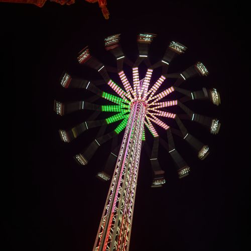 Free A vibrant illuminated amusement ride photographed from below at night. Stock Photo